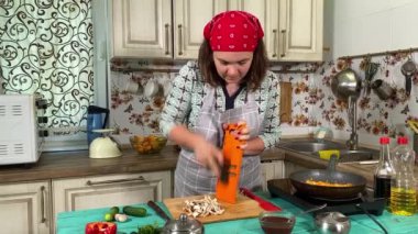 Mutfak konsepti, ev yapımı yemekler için hazırlama malzemeleri. Önlüklü genç bir kadın yemek pişiriyor, mutfak tezgahında sebze rendeliyor. Ev yemeği ve gastronomi tutkusu.