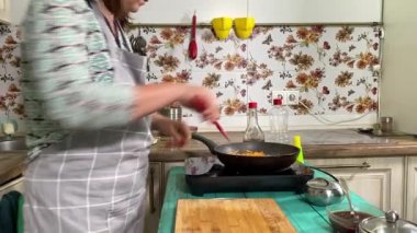 Mutfak konsepti, ev yapımı yemekler için hazırlama malzemeleri. Önlüklü, yemek pişiren genç ve güzel bir kadın mutfak tezgahında mirepoix yapıyor. Ev yemeği ve gastronomi tutkusu.