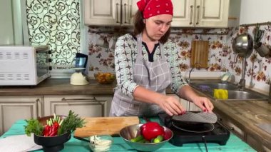 Mutfak konsepti, ev yapımı yemekler için hazırlama malzemeleri. Önlüklü genç bir kadın yemek pişiriyor, mutfak tezgahında sebzeli börek yapıyor. Ev yemeği ve gastronomi.