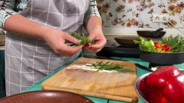 Mutfak konsepti, ev yapımı yemekler için hazırlama malzemeleri. Önlüklü genç bir kadın yemek pişiriyor, mutfak tezgahında sebzeli börek yapıyor. Ev yemeği ve gastronomi.