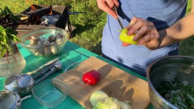 Yakışıklı bir beyaz adam açık hava barbeküsü için malzeme hazırlıyor. Açık ateşte leziz bir yemek. Bahçede yemek pişirmenin rahatlatıcı atmosferine sahip olmanın keyfi. BBQ konsepti