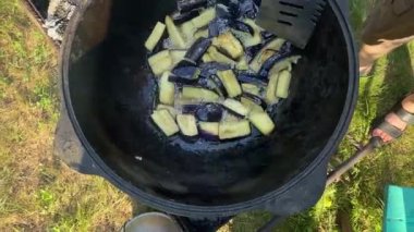 Yakışıklı beyaz bir adam arka bahçedeki ızgaranın üzerinde kazanda lezzetli bir yemek hazırlıyor. Açık hava yemekleri, barbekü geleneği, arka bahçe eğlencesi, gevşeme konusunda aşçılık becerileri. BBQ konsepti
