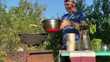 Yakışıklı beyaz bir adam arka bahçedeki ızgaranın üzerinde kazanda lezzetli bir yemek hazırlıyor. Açık hava yemekleri, barbekü geleneği, arka bahçe eğlencesi, gevşeme konusunda aşçılık becerileri. BBQ konsepti