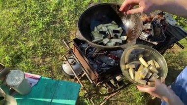 Yakışıklı beyaz bir adam arka bahçedeki ızgaranın üzerinde kazanda lezzetli bir yemek hazırlıyor. Açık hava yemekleri, barbekü geleneği, arka bahçe eğlencesi, gevşeme konusunda aşçılık becerileri. BBQ konsepti