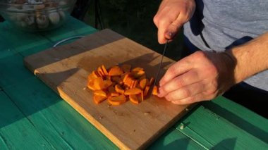 Yakışıklı bir beyaz adam açık hava barbeküsü için malzeme hazırlıyor. Açık ateşte leziz bir yemek. Bahçede yemek pişirmenin rahatlatıcı atmosferine sahip olmanın keyfi. BBQ konsepti