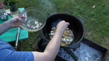 Yakışıklı beyaz bir adam arka bahçedeki ızgaranın üzerinde kazanda lezzetli bir yemek hazırlıyor. Açık hava yemekleri, barbekü geleneği, arka bahçe eğlencesi, gevşeme konusunda aşçılık becerileri. BBQ konsepti