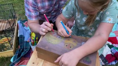 Genç bir baba ve kızı arka bahçede evcil kemirgenlerle ilgilenerek birlikte kaliteli vakit geçirmenin keyfini çıkarıyorlar. Aile ve çocuk, küçük hayvanlarına sevgi dolu bir şekilde açık hava ortamında bakıyorlar.