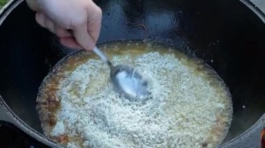 Yakışıklı beyaz bir adam arka bahçedeki ızgaranın üzerinde kazanda lezzetli bir yemek hazırlıyor. Açık hava yemekleri, barbekü geleneği, arka bahçe eğlencesi, gevşeme konusunda aşçılık becerileri. BBQ konsepti