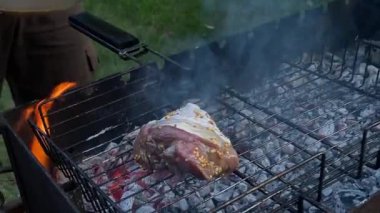 Yakışıklı beyaz bir adam arka bahçedeki ızgarada yemek hazırlıyor, açık hava yemeklerinin tadını çıkarıyor. Et ızgarası üzerine yoğunlaşıyor. Ev ortamında rahatça yemek pişirme becerileri. BBQ konsepti