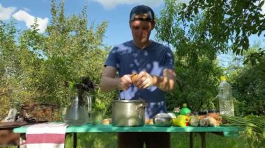 Yakışıklı bir beyaz adam açık hava barbeküsü için malzeme hazırlıyor. Açık ateşte leziz bir yemek. Bahçede yemek pişirmenin rahatlatıcı atmosferine sahip olmanın keyfi. BBQ konsepti