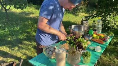 Yakışıklı bir beyaz adam açık hava barbeküsü için malzeme hazırlıyor. Açık ateşte leziz bir yemek. Bahçede yemek pişirmenin rahatlatıcı atmosferine sahip olmanın keyfi. BBQ konsepti
