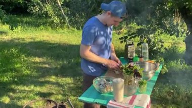 Yakışıklı bir beyaz adam açık hava barbeküsü için malzeme hazırlıyor. Açık ateşte leziz bir yemek. Bahçede yemek pişirmenin rahatlatıcı atmosferine sahip olmanın keyfi. BBQ konsepti