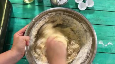 Genç ve çekici bir ev hanımı ev mutfağında hamur mayası hazırlıyor. Kadın malzemeleri karıştırıyor, mükemmel bir temel oluşturmak için hamur üzerinde hassasiyetle çalışıyor. Geleneksel pişirme ve ev yapımı aşçılık becerileri