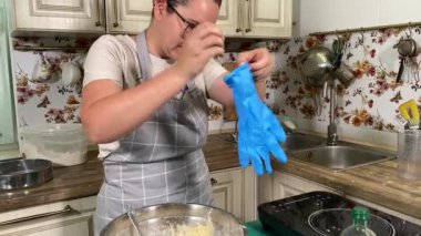 Genç ve çekici bir ev hanımı ev mutfağında hamur mayası hazırlıyor. Kadın malzemeleri karıştırıyor, mükemmel bir temel oluşturmak için hamur üzerinde hassasiyetle çalışıyor. Geleneksel pişirme ve ev yapımı aşçılık becerileri