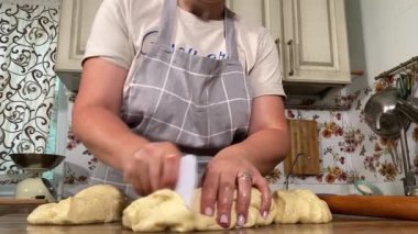 Genç ve çekici bir ev hanımı sıcak mutfağında ev yapımı elmalı turta hazırlıyor. Çekici kadın hamur mayası ve elma dolgusu ile geleneksel pişirme yöntemlerini vurgulayarak ustalıkla çalışıyor.