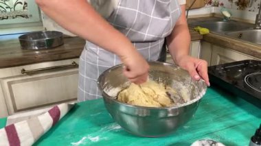 Genç ve çekici bir ev hanımı ev mutfağında hamur mayası hazırlıyor. Kadın malzemeleri karıştırıyor, mükemmel bir temel oluşturmak için hamur üzerinde hassasiyetle çalışıyor. Geleneksel pişirme ve ev yapımı aşçılık becerileri