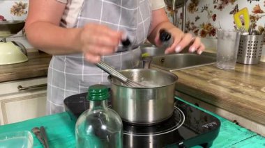 Genç ve çekici bir ev hanımı ev mutfağında hamur mayası hazırlıyor. Kadın malzemeleri karıştırıyor, mükemmel bir temel oluşturmak için hamur üzerinde hassasiyetle çalışıyor. Geleneksel pişirme ve ev yapımı aşçılık becerileri