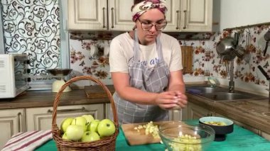 Genç ve çekici bir ev hanımı sıcak mutfağında ev yapımı elmalı turta hazırlıyor. Çekici kadın hamur mayası ve elma dolgusu ile geleneksel pişirme yöntemlerini vurgulayarak ustalıkla çalışıyor.