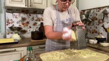 Genç ve çekici bir ev hanımı sıcak mutfağında ev yapımı elmalı turta hazırlıyor. Çekici kadın hamur mayası ve elma dolgusu ile geleneksel pişirme yöntemlerini vurgulayarak ustalıkla çalışıyor.