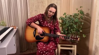Şık elbiseli ve gözlüklü güzel bir genç kadın evde çalışırken bir müzik aleti çalar. İçeride yaratıcılığın ve adanmışlığın huzurlu bir anı. Hobi ve boş zaman