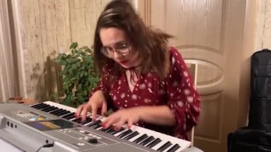 Şık elbiseli ve gözlüklü güzel bir genç kadın evde çalışırken bir müzik aleti çalar. İçeride yaratıcılığın ve adanmışlığın huzurlu bir anı. Hobi ve boş zaman
