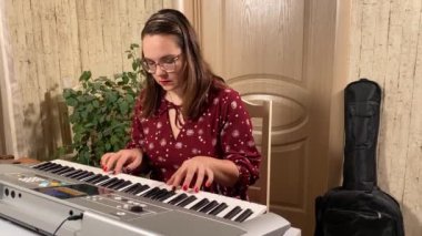 Şık elbiseli ve gözlüklü güzel bir genç kadın evde çalışırken bir müzik aleti çalar. İçeride yaratıcılığın ve adanmışlığın huzurlu bir anı. Hobi ve boş zaman