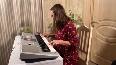 Şık elbiseli ve gözlüklü güzel bir genç kadın evde çalışırken bir müzik aleti çalar. İçeride yaratıcılığın ve adanmışlığın huzurlu bir anı. Hobi ve boş zaman