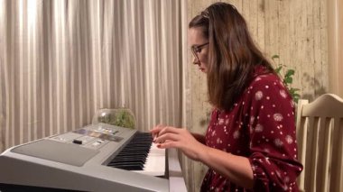 Şık elbiseli ve gözlüklü güzel bir genç kadın evde çalışırken bir müzik aleti çalar. İçeride yaratıcılığın ve adanmışlığın huzurlu bir anı. Hobi ve boş zaman
