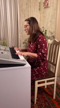 Şık elbiseli ve gözlüklü güzel bir genç kadın evde çalışırken dijital piyano çalar. İçeride yaratıcılığın ve adanmışlığın huzurlu bir anı. Hobi ve boş zaman