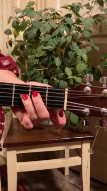 Şık elbiseli ve gözlüklü güzel bir genç kadın evde çalışırken gitar çalar. İçeride yaratıcılığın ve adanmışlığın huzurlu bir anı. Hobi ve boş zaman
