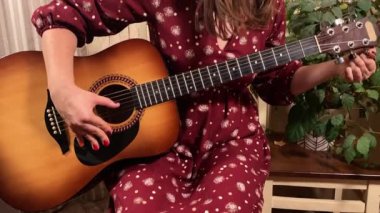 Şık elbiseli ve gözlüklü güzel bir genç kadın evde çalışırken gitar çalar. İçeride yaratıcılığın ve adanmışlığın huzurlu bir anı. Hobi ve boş zaman