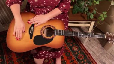 Şık elbiseli ve gözlüklü güzel bir genç kadın evde çalışırken gitar çalar. İçeride yaratıcılığın ve adanmışlığın huzurlu bir anı. Hobi ve boş zaman