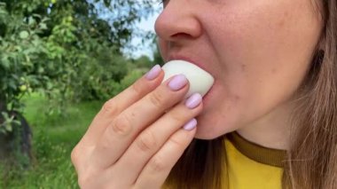 Güzel genç bir kadın ağaçlarla çevrili yemyeşil bir parkta gündelik bir öğle yemeğinin tadını çıkarıyor. Rahatlayarak ve yemeğin tadını çıkararak, temiz hava ve doğada biraz dinlenir..