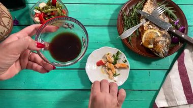 Lezzetli yemeklerle dolu kırsal bir yemek masası manzarası. Dişi eller yemeği hazırlar ve keyfini çıkarırlar. Kapalı mekanlar ev yapımı yemeklerin ve özenli yemeklerin neşesini ön plana çıkarıyor. 