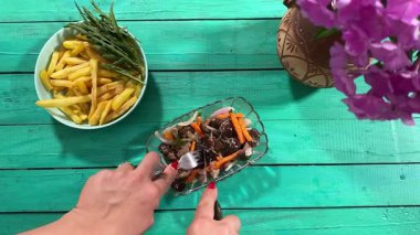 Lezzetli yemeklerle dolu kırsal bir yemek masası manzarası. Dişi eller yemeği hazırlar ve keyfini çıkarırlar. Kapalı mekanlar ev yapımı yemeklerin ve özenli yemeklerin neşesini ön plana çıkarıyor. 