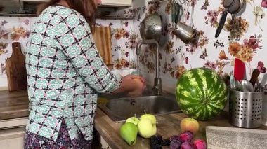 İçerideki sulu meyvelerin tadını çıkaran genç bir kadın taze ve sağlıklı tadını çıkarıyor. Rahatlamış ve memnun, sakin ve rahat bir atmosferde sağlıklı beslenmenin basit zevkini kucaklıyor..