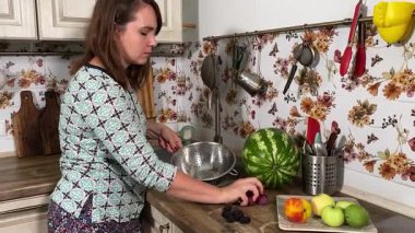 İçerideki sulu meyvelerin tadını çıkaran genç bir kadın taze ve sağlıklı tadını çıkarıyor. Rahatlamış ve memnun, sakin ve rahat bir atmosferde sağlıklı beslenmenin basit zevkini kucaklıyor..