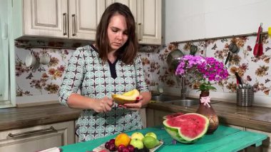 İçerideki sulu meyvelerin tadını çıkaran genç bir kadın taze ve sağlıklı tadını çıkarıyor. Rahatlamış ve memnun, sakin ve rahat bir atmosferde sağlıklı beslenmenin basit zevkini kucaklıyor..