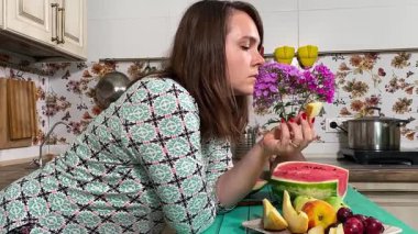 İçerideki sulu meyvelerin tadını çıkaran genç bir kadın taze ve sağlıklı tadını çıkarıyor. Rahatlamış ve memnun, sakin ve rahat bir atmosferde sağlıklı beslenmenin basit zevkini kucaklıyor..