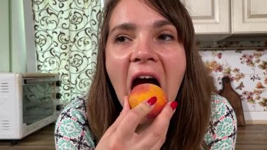 İçerideki sulu meyvelerin tadını çıkaran genç bir kadın taze ve sağlıklı tadını çıkarıyor. Rahatlamış ve memnun, sakin ve rahat bir atmosferde sağlıklı beslenmenin basit zevkini kucaklıyor..