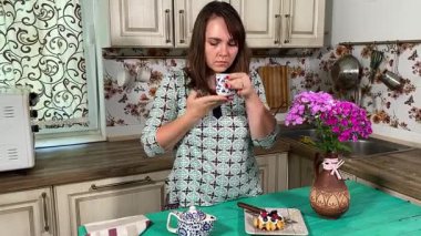 İçerideki genç bayan tatlı bir tart yiyip sıcak çay yudumluyor. Sıcak bir içecekle, sakin, rahat bir hoşgörü atmosferinde mükemmel bir şekilde eşleştirerek, zengin tatlı tadını çıkarıyor..