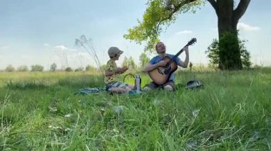Küçük baba ve oğlu yaz pikniğinin tadını çıkarıyor, birlikte güzel vakit geçiriyorlar. Dışarıdaki eğlenceli aktivitelere katılıyorlar, sıcak güneşin altında mutlu anılar yaratıyorlar.