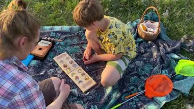 Küçük baba ve oğlu yaz pikniğinin tadını çıkarıyor, birlikte güzel vakit geçiriyorlar. Dışarıdaki eğlenceli aktivitelere katılıyorlar, sıcak güneşin altında mutlu anılar yaratıyorlar.