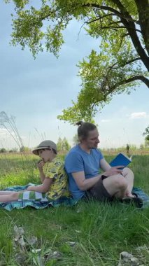 Dikey genç baba ve oğul yaz pikniğinin tadını çıkarıyor, birlikte güzel vakit geçiriyorlar. Dışarıdaki eğlenceli aktivitelere katılıyorlar, sıcak güneşin altında mutlu anılar yaratıyorlar.