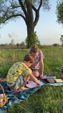 Dikey genç baba ve oğul yaz pikniğinin tadını çıkarıyor, birlikte güzel vakit geçiriyorlar. Dışarıdaki eğlenceli aktivitelere katılıyorlar, sıcak güneşin altında mutlu anılar yaratıyorlar.