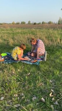 Dikey genç baba ve oğul yaz pikniğinin tadını çıkarıyor, birlikte güzel vakit geçiriyorlar. Dışarıdaki eğlenceli aktivitelere katılıyorlar, sıcak güneşin altında mutlu anılar yaratıyorlar.