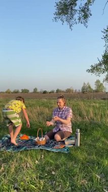 Dikey genç baba ve oğul yaz pikniğinin tadını çıkarıyor, birlikte güzel vakit geçiriyorlar. Dışarıdaki eğlenceli aktivitelere katılıyorlar, sıcak güneşin altında mutlu anılar yaratıyorlar.