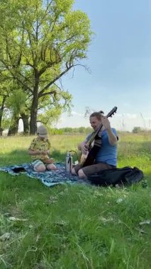 Dikey genç baba ve oğul yaz pikniğinin tadını çıkarıyor, birlikte güzel vakit geçiriyorlar. Dışarıdaki eğlenceli aktivitelere katılıyorlar, sıcak güneşin altında mutlu anılar yaratıyorlar.