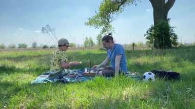 Küçük baba ve oğlu yaz pikniğinin tadını çıkarıyor, birlikte güzel vakit geçiriyorlar. Dışarıdaki eğlenceli aktivitelere katılıyorlar, sıcak güneşin altında mutlu anılar yaratıyorlar.