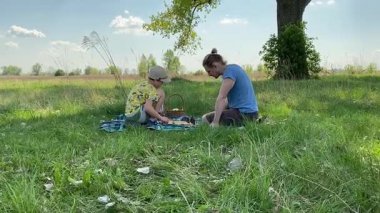 Küçük baba ve oğlu yaz pikniğinin tadını çıkarıyor, birlikte güzel vakit geçiriyorlar. Dışarıdaki eğlenceli aktivitelere katılıyorlar, sıcak güneşin altında mutlu anılar yaratıyorlar.